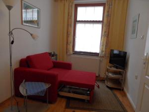 a living room with a red couch and a tv at Parterrewohnung in Wismar
