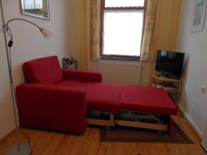 ein Wohnzimmer mit einem roten Sofa und einem TV in der Unterkunft Parterrewohnung in Wismar
