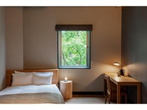 a bedroom with a bed and a desk and a window at HOTEL KARUIZAWA CROSS - Vacation STAY 56455v in Karuizawa