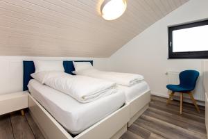 two beds in a small room with a blue chair at Kyst 3 in Neustadt in Holstein