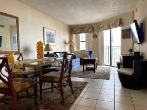 a living room with a table and chairs and a television at Beachfront Condo Ocean View in St Pete Beach