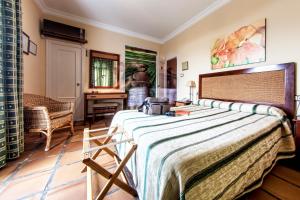 a bedroom with a large bed and a desk at Hotel Albaida Nature in Mazagón