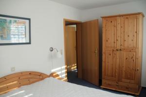 a bedroom with a bed and a wooden cabinet at Boddenwelle in Zingst