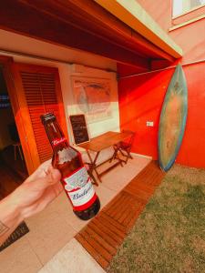 a hand holding a bottle of beer in front of a building at MADÁ hostel in São Paulo