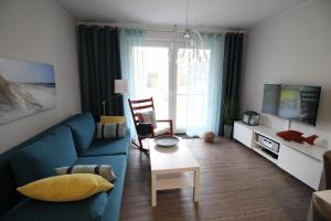 ein Wohnzimmer mit einem blauen Sofa und einem TV in der Unterkunft Dock 31 in Dierhagen