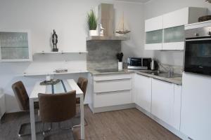 eine weiße Küche mit einem Tisch und einer Mikrowelle in der Unterkunft Dock 31 in Dierhagen
