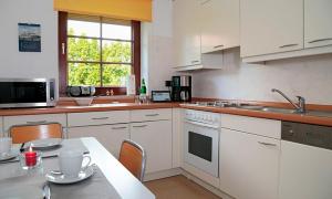 a kitchen with white cabinets and a table and a window at Haus Birkenweg in Westerrönfeld