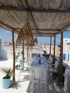 - une table et des chaises sous un parasol de paille sur une terrasse dans l'établissement Dar Evelyne, à Mahdia