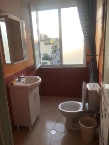 a bathroom with a toilet and a sink and a window at Apartment Majlinda in Tirana
