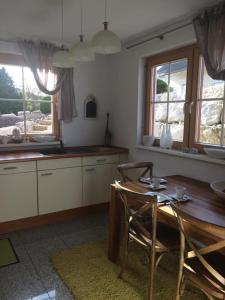 eine Küche mit einem Holztisch, Stühlen und Fenstern in der Unterkunft Braunkehlchen in Straubenhardt