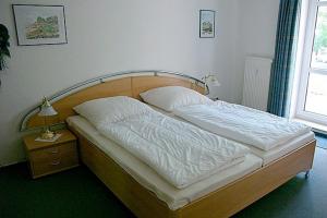 a bed with a wooden headboard and white pillows at Residenz "Am Postplatz", Villa Sonja, Whg 9 in Zingst