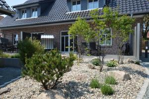 a garden in front of a house with trees and rocks at Stadthaus 1, inkl 1 Parkplatz in Burg auf Fehmarn