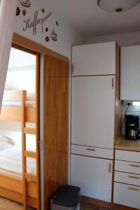 a bedroom with a bunk bed and a white refrigerator at Hinzberg, P-EG-4 in Heiligenhafen