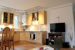 a kitchen with wooden cabinets and a flat screen tv at Strandvilla Sophie App 2 in Dierhagen