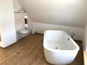 a bathroom with a white tub and a toilet at Nordische Ferienwohnung auf Gut Bennewohld LL in Heide