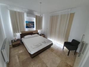 1 dormitorio con 1 cama blanca y 1 silla en St. Georgiana Villa 7, en Peyia