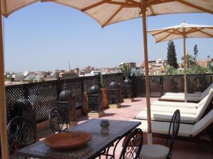 eine Terrasse mit einem Tisch, Stühlen und einem Sonnenschirm in der Unterkunft Riad Marrakiss in Marrakesch