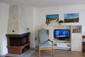 a living room with a fireplace and a chair and a television at Pastoratshof - Whg2 in Wrixum