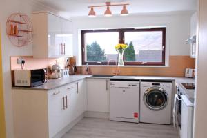 a kitchen with a washing machine and a window at Premium Ground Floor Apartment, Near Fort William Town Centre in Fort William +13 photos