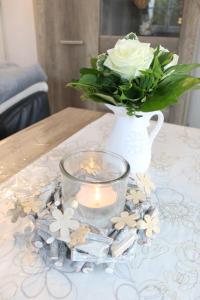 a vase with a white rose and a candle on a table at Ferienwohnung Steffens - "Lübecker Straße" in Grömitz