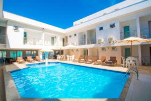 a pool with chairs and umbrellas next to a building at Shangrilá - Rede Soberano in Porto Seguro