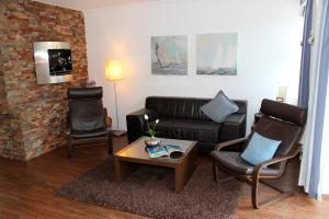 a living room with a leather couch and two chairs at LANDHAUS AM HAFEN im EG in Heiligenhafen