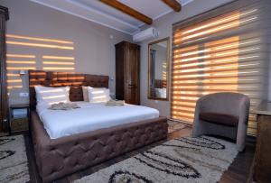 a bedroom with a large bed and a chair at Garni Hotel Kaća in Kragujevac