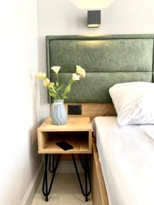 a vase with flowers on a night stand next to a bed at Апарт-отель Nine Rooms in Yerevan