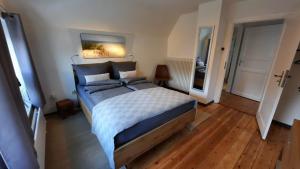 a bedroom with a large bed and wooden floors at De Lüdde Mangelstuv in Bredstedt