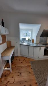 eine Küche mit weißen Schränken, einem Waschbecken und einem Fenster in der Unterkunft De Lüdde Mangelstuv in Bredstedt