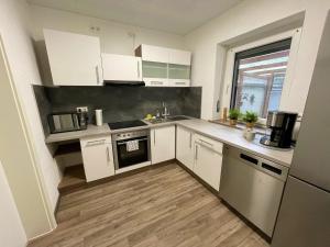 a kitchen with white cabinets and a wooden floor at Ferienwohnung Kutscher in Bad Ems