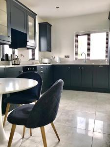 una cocina con armarios negros, mesa y sillas en Sperrin View, en Omagh