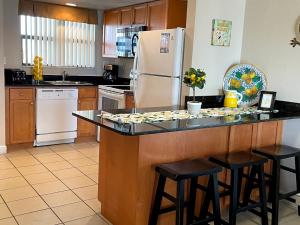 a kitchen with a counter with a refrigerator and stools at Beachfront Condo Ocean View in St Pete Beach