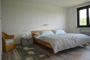 a bedroom with a bed and a chair and a window at Naturparadies & Abenteuer schwäbische Alb in Großbettlingen