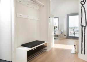 una sala de estar con una pared blanca y un banco en Ostsee - Appartement Nr 55 "Marina Loft" im Strand Resort, en Heiligenhafen