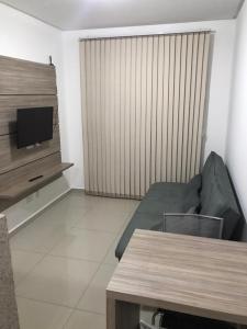 uma sala de estar com um sofá e uma TV de tela plana em Flat Essenciale Style 1506 em Goiânia