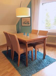 uma mesa de jantar em madeira com cadeiras e um candeeiro em Haus am Kurpark - Strandmuschel em Grömitz