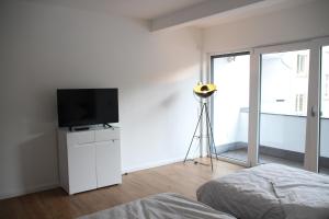 1 dormitorio con TV en un tocador con cama en Casa Kronengarten Nr 4, en Hilden