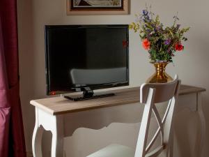 a television sitting on a table with a vase of flowers at Torre Della Chiocciola in Monteriggioni