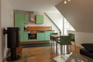 a kitchen with green cabinets and a table with chairs at Gustavs Apartment in Zingst