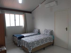 1 dormitorio con 2 camas y ventana en Suites Praia de Juquehy en Juquei