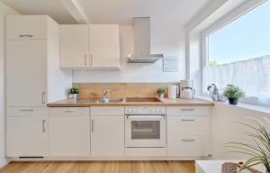 eine Küche mit weißen Schränken, einem Waschbecken und einem Fenster in der Unterkunft Backhaus West in Bisdorf
