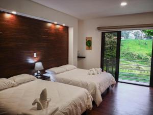 a bedroom with two beds and a large window at Burbi Lake Lodge Monteverde in Monteverde Costa Rica +48 photos