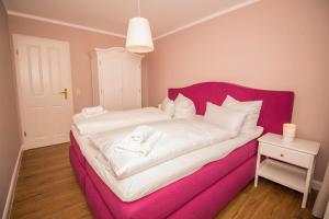 ein rosa Bett mit weißer Bettwäsche auf einem Zimmer in der Unterkunft FerienDüne 1 in Kägsdorf