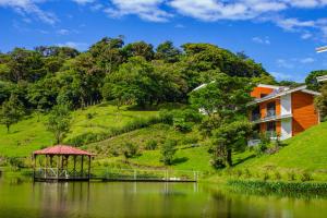 a house on a hill next to a lake with a gazebo at Burbi Lake Lodge Monteverde in Monteverde Costa Rica