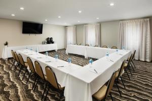 a conference room with tables and chairs and a screen at Staybridge Suites Of Durham - Chapel Hill - RTP by IHG in Durham