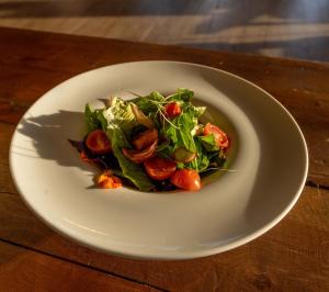 a white plate with a salad on a wooden table at Estancia Cerro Guido in Torres del Paine