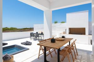 a patio with a table and chairs and a swimming pool at Seacarf Villa, 3 magnificent properties in Lachania beach, Bedrooms 12, Sleeps 27 in Lachania