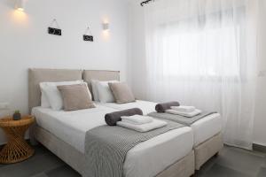 a white bedroom with two beds with towels on them at Seacarf Villa, 3 magnificent properties in Lachania beach, Bedrooms 12, Sleeps 27 in Lachania +43 photos