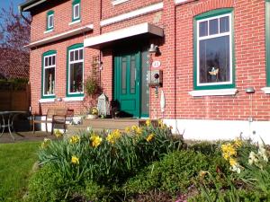 uma casa de tijolos vermelhos com uma porta verde e flores em FW Einfeldt em Hinrichsdorf